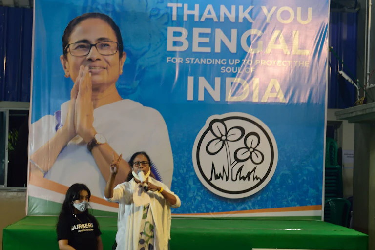 Mamata Banerjee, the chief minister of West Bengal, makes a victory sign in front of an election poster.