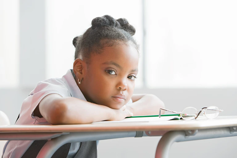 A young child places her head down on a book.