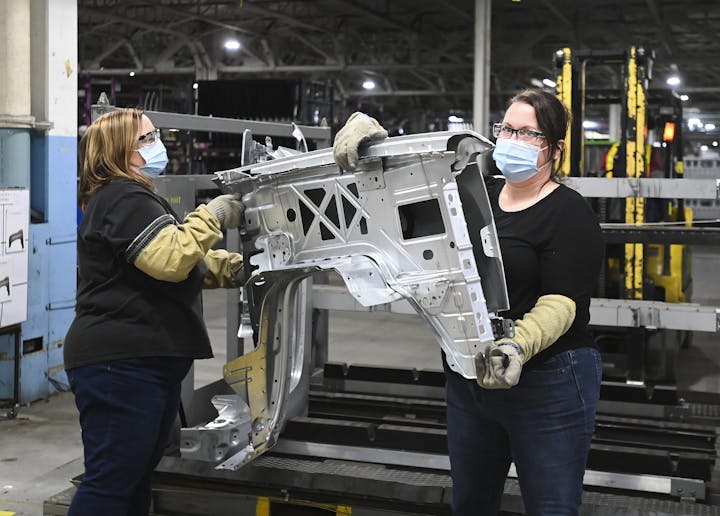  GM workers place vehicle truck fenders on a rack at the General Motors assembly plant during the COVID-19 pandemic in Oshawa, Ont., in March 2021. Unionized workers have fared better during the crisis. (The Canadian Press/Nathan Denette)