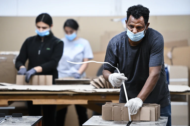 Factory workers wear masks and gloves
