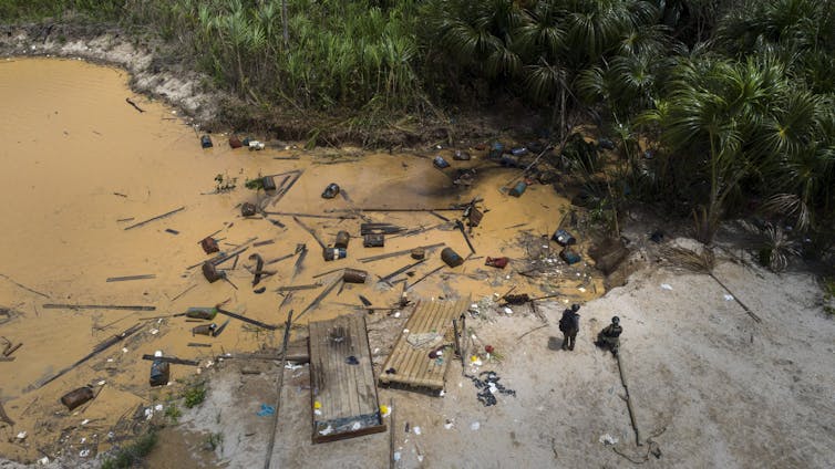 broken camp materials on the shores of a polluted river