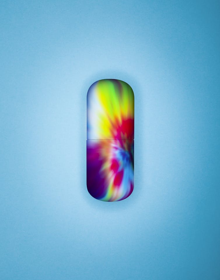 Rainbow pill capsule on blue background.