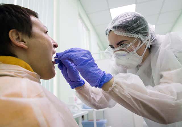 Medical worker takes a viral swab from a patient's mouth