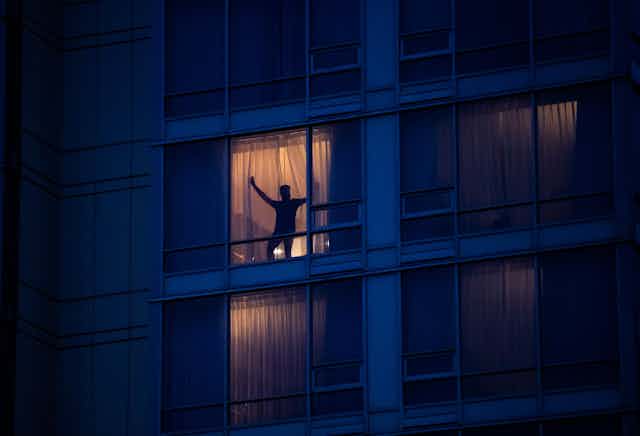 Man stands in window of hotel