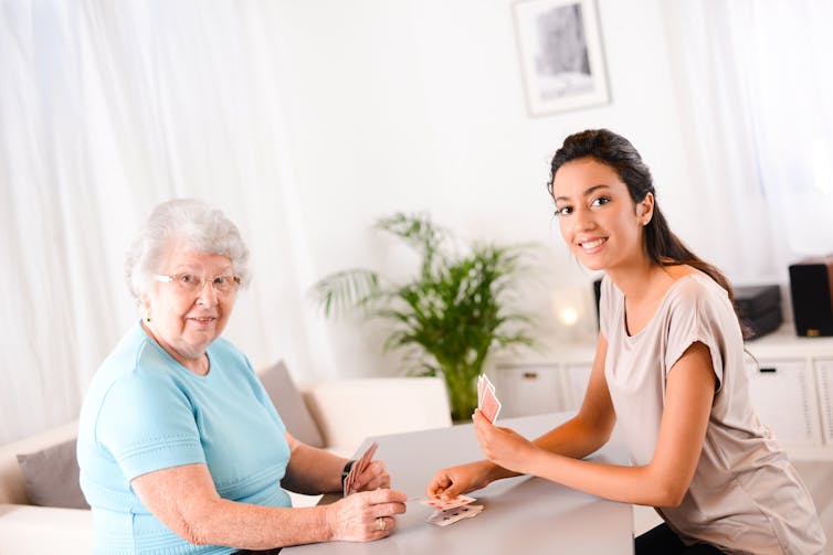An older woman playing cards with a younger woman