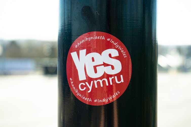 A sticker on a lamppost reading 'Yes Cymru'.