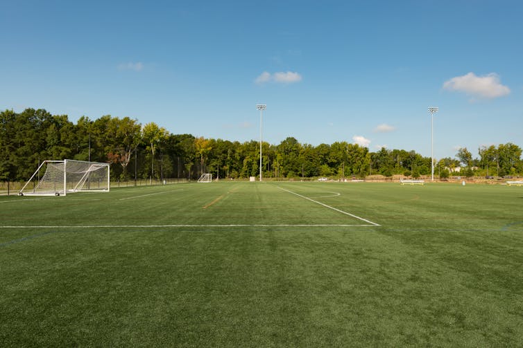 A neatly mown football field in a public park.