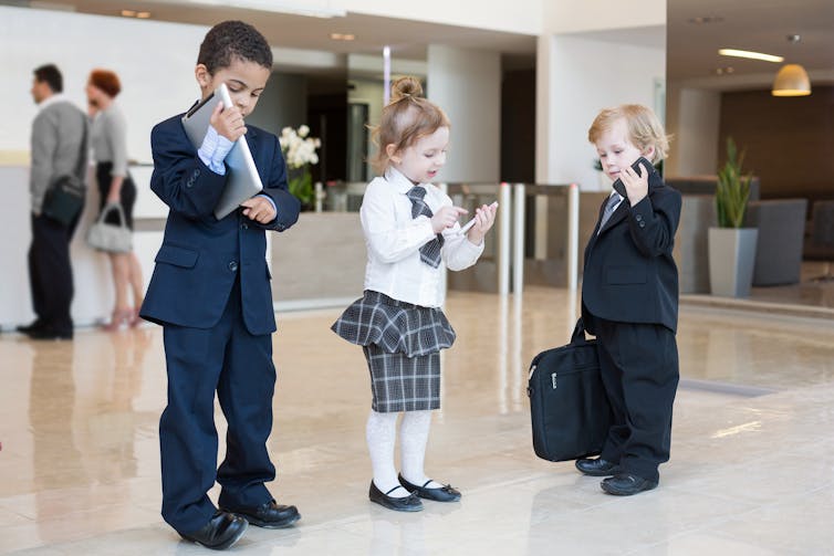 Three children dressed as if they're workers in an office