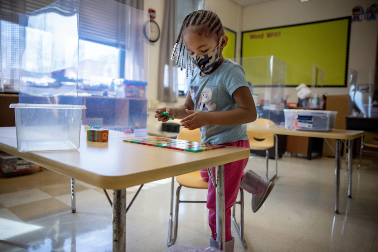 Preschool child works at a classroom desk