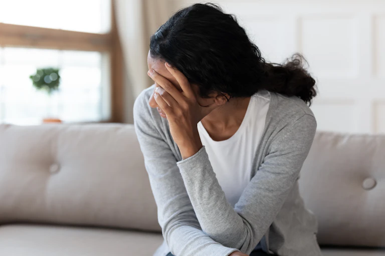 Woman sitting with her hand covering her face
