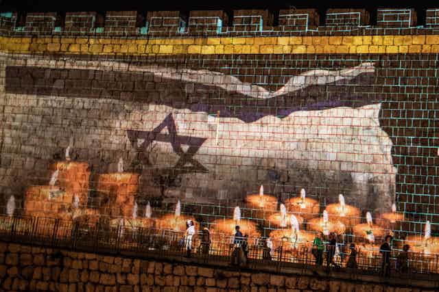 A condolence message and candles for the victims of a stampede during a Jewish ultra-Orthodox mass pilgrimage to Mount Meron is projected on a wall of Jerusalem's Old City.