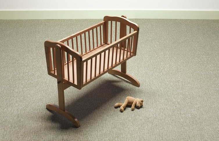 Empty crib with a stuffed animal lying beside it. miscarriage