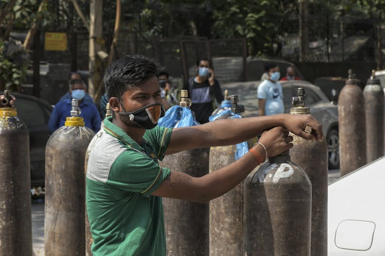 People wait in line to refill oxygen cylinders.