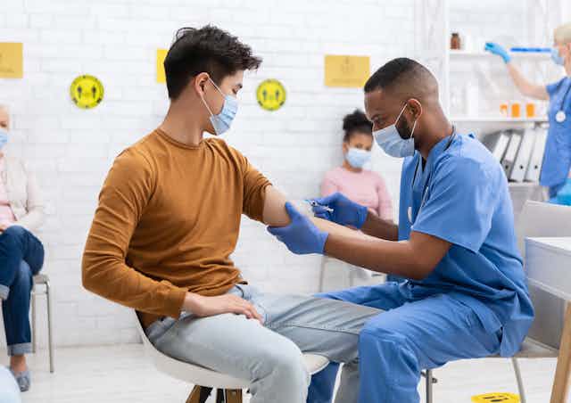 A health-care worker giving an injection to a young adult