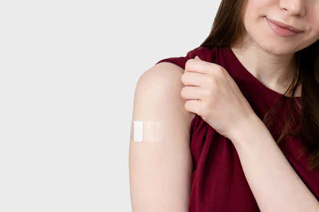 Woman showing vaccine plaster on arm