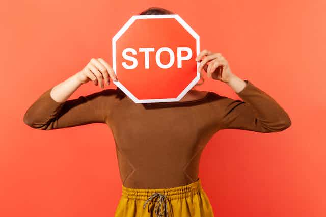 Una señal de Stop tapando la cara de una mujer.