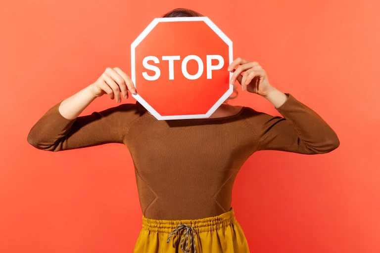 Una señal de Stop tapando la cara de una mujer.