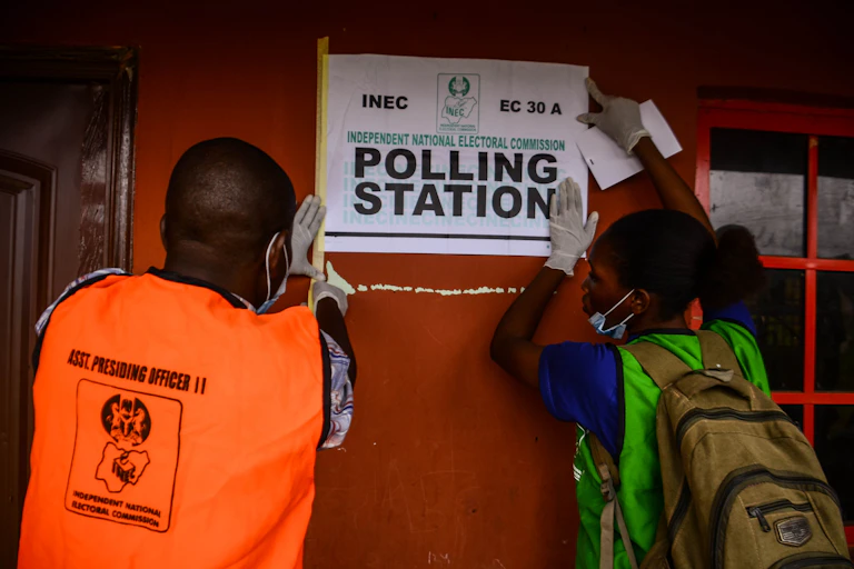 Polling station workers adding posters on the wall at polling unit 26, ward 5, Iguododo, Orhionmwon Local Government Area, in Edo State, on September 19 , 2020.