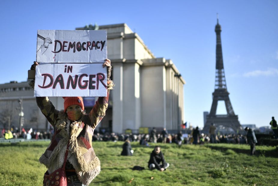 Une femme brandit une pancarte « Démocratie en danger » à Paris
