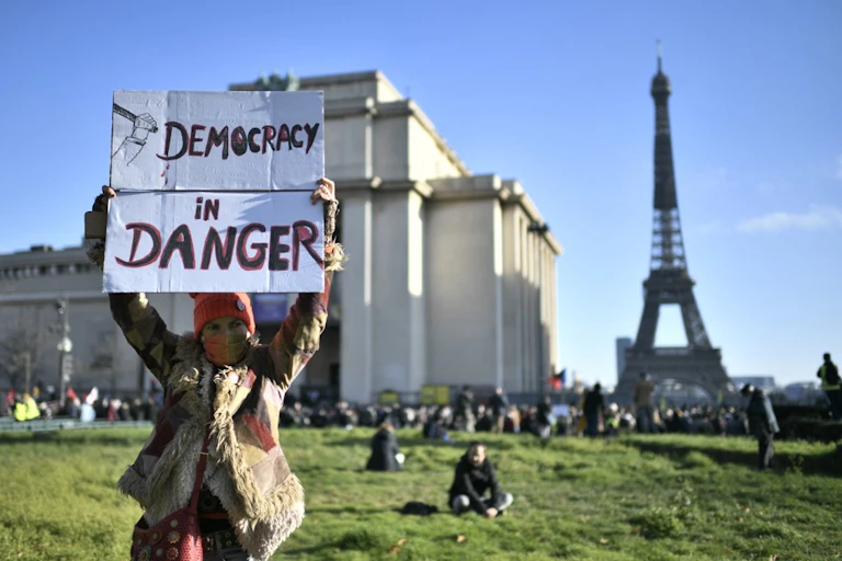Une femme brandit une pancarte « Démocratie en danger » à Paris