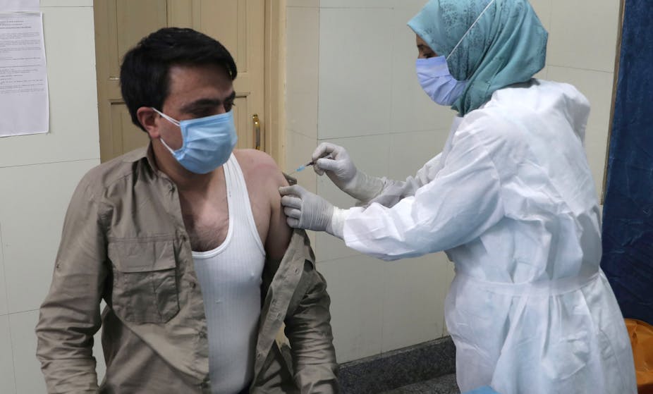 A man in India being vaccinated by a nurse