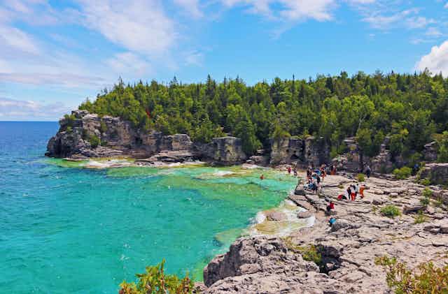 People explore the turquoise waters and the rocks of the Bruce Peninsula.