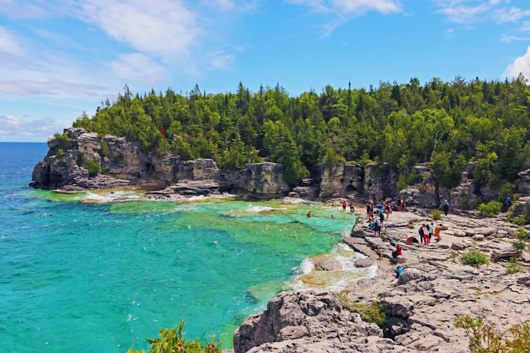 People explore the turquoise waters and the rocks of the Bruce Peninsula.