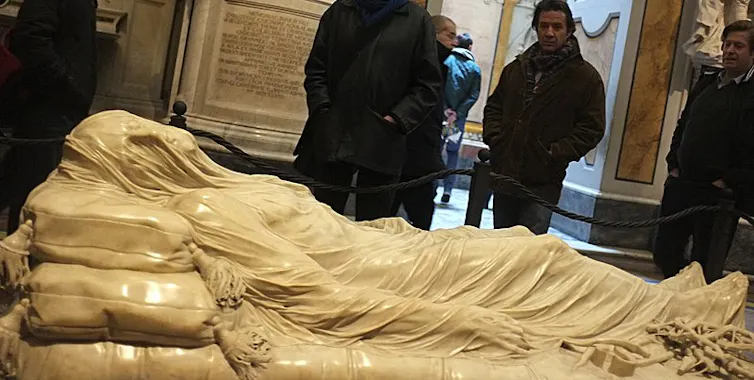 Marble statue of Christ, shown lying down and covered from head to toe with a veila