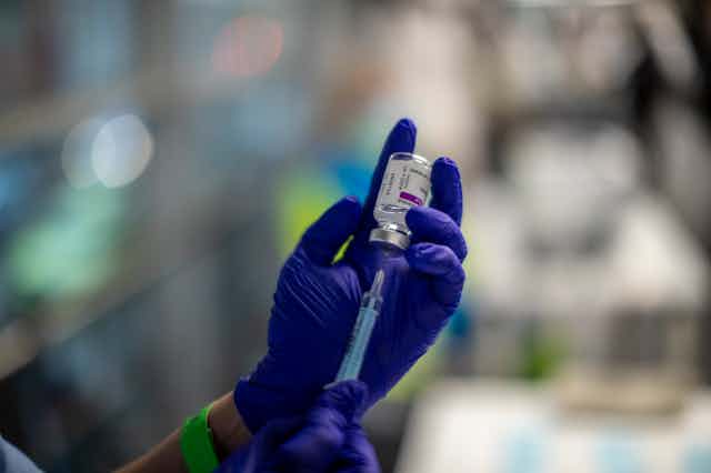 A health worker holding a vial of the AstraZeneca COVID-19 vaccine