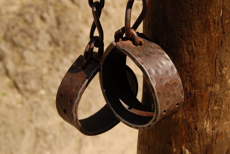Metal chains with hand shackles hanging off post