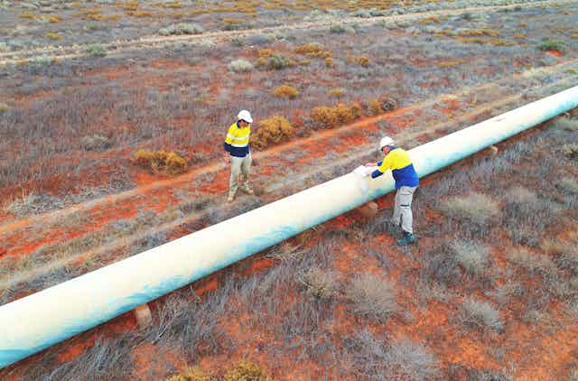 two men inspect a water pipeline
