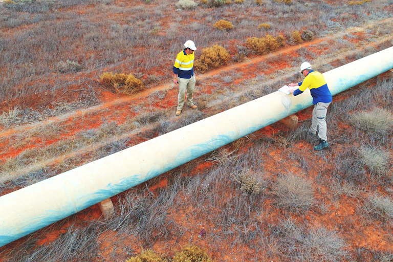 two men inspect a water pipeline