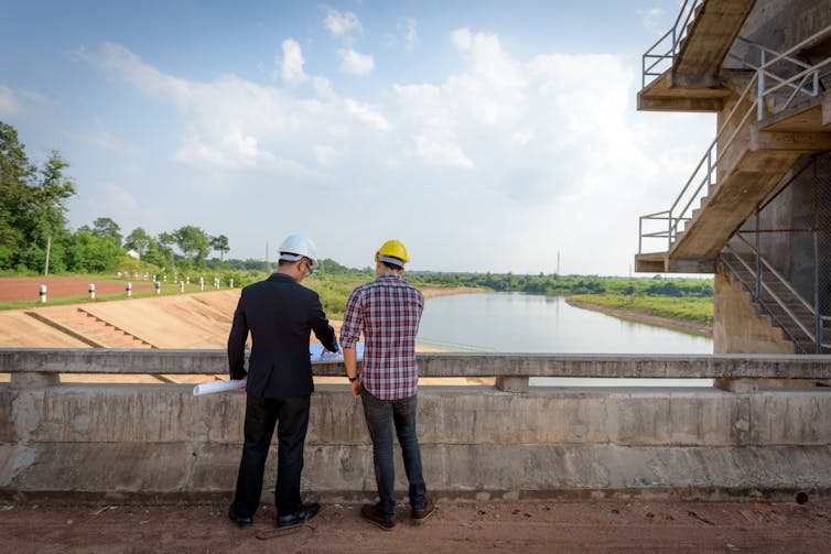 two male engineers look at dam
