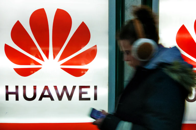 A woman on her phone walking by Huawei signs