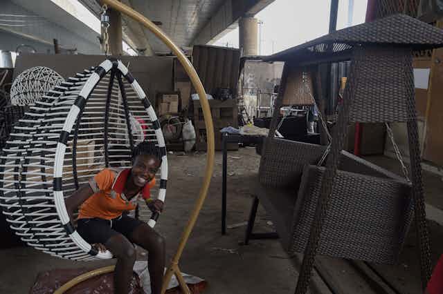 A child sits on a cane woven chair