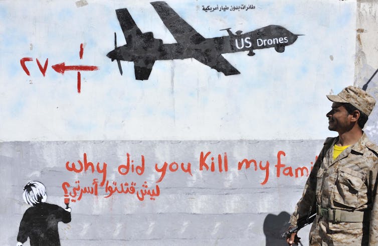 A Yemeni soldier looks at the graffiti of U.S. drone strike painted on a wall as a protest against the drone strikes, in Sanaa, Yemen