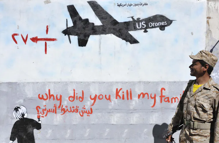 Un soldat yéménite regarde un graffiti sur un mur à Sanaa, au Yemen