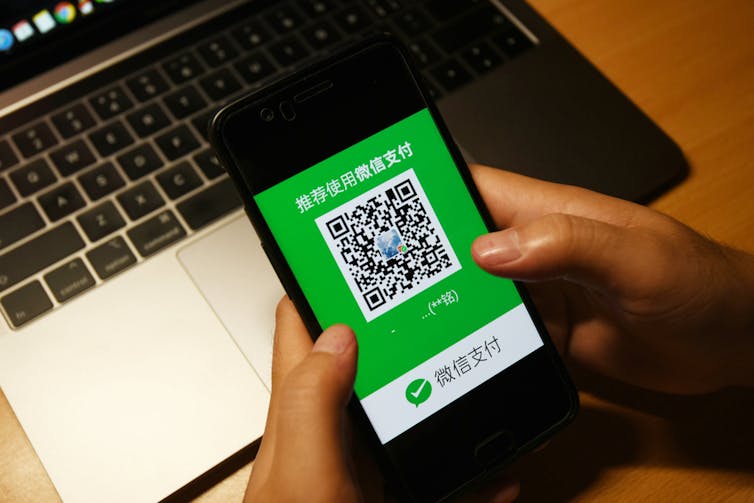 Alguien sosteniendo un teléfono inteligente usando la aplicación WeChat para realizar un pago