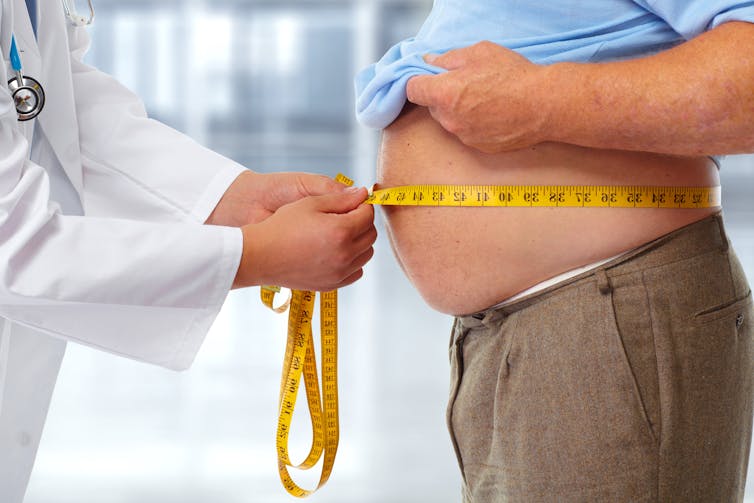 Doctor measure's an obese man's stomach.