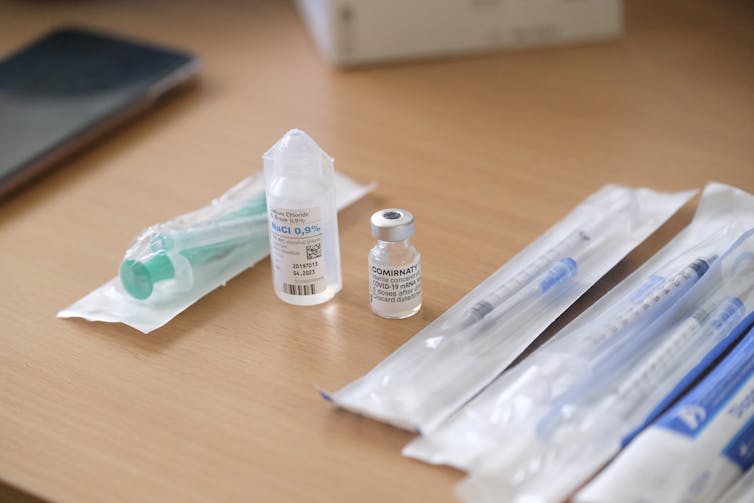 Vaccine vial and syringes arrayed on a desk.