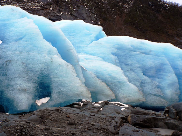 Bright blue glacier ice on rocky terrain.