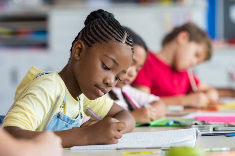 A young girl writes in a notebook.
