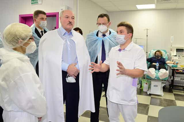 Lukashenko stands in a hospital ward surrounded by doctors in full protective equipment