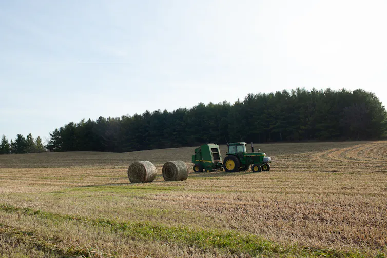 A tractor and two round bales of hay on a sunny day in Wellington County, Ontario