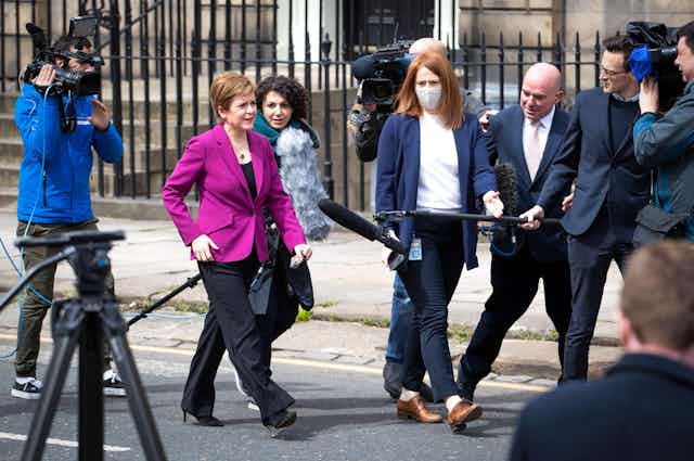 Nicola Sturgeon walks down an Edinburgh Street as she talks to the press. 