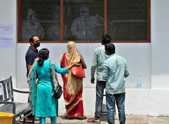 Family members talk to paramedics at a hospital in India.