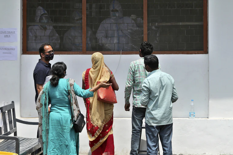 Family members talk to paramedics at a hospital in India.