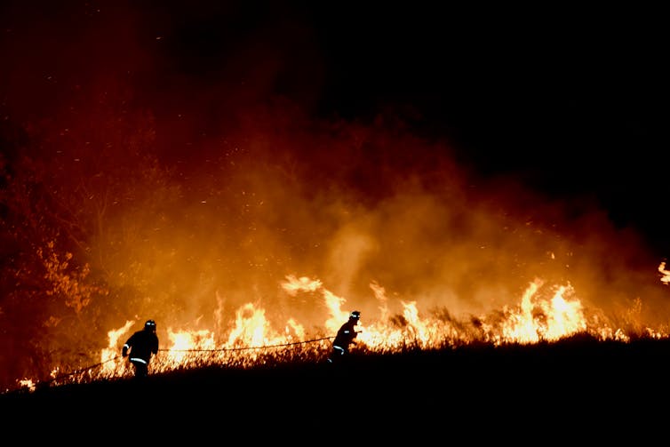 firefighters run past fire