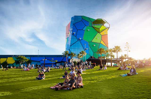 A colourful gallery rises above green grass