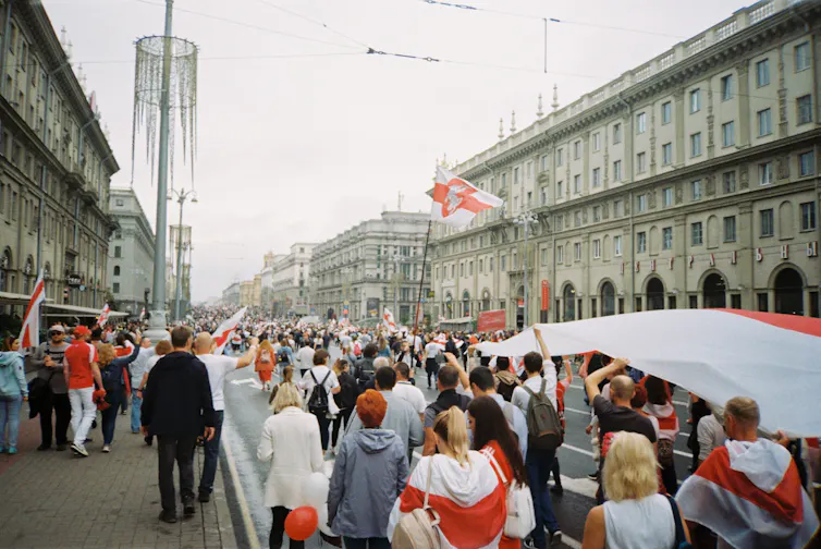 A crowd carrying red and white flags protests on a Belarussian street in winter
